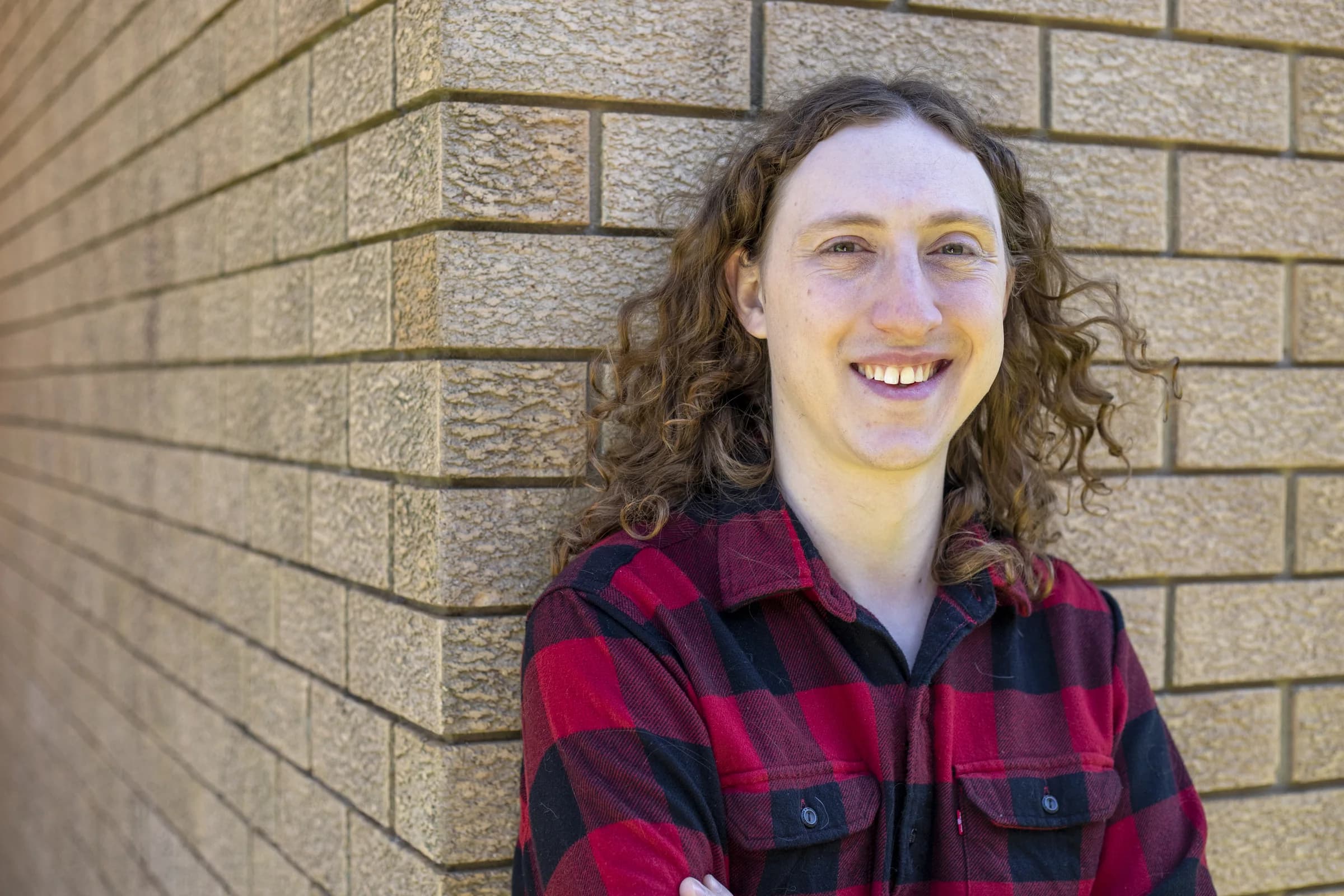 Author Jordan King-Lacroix smiling against a brick wall